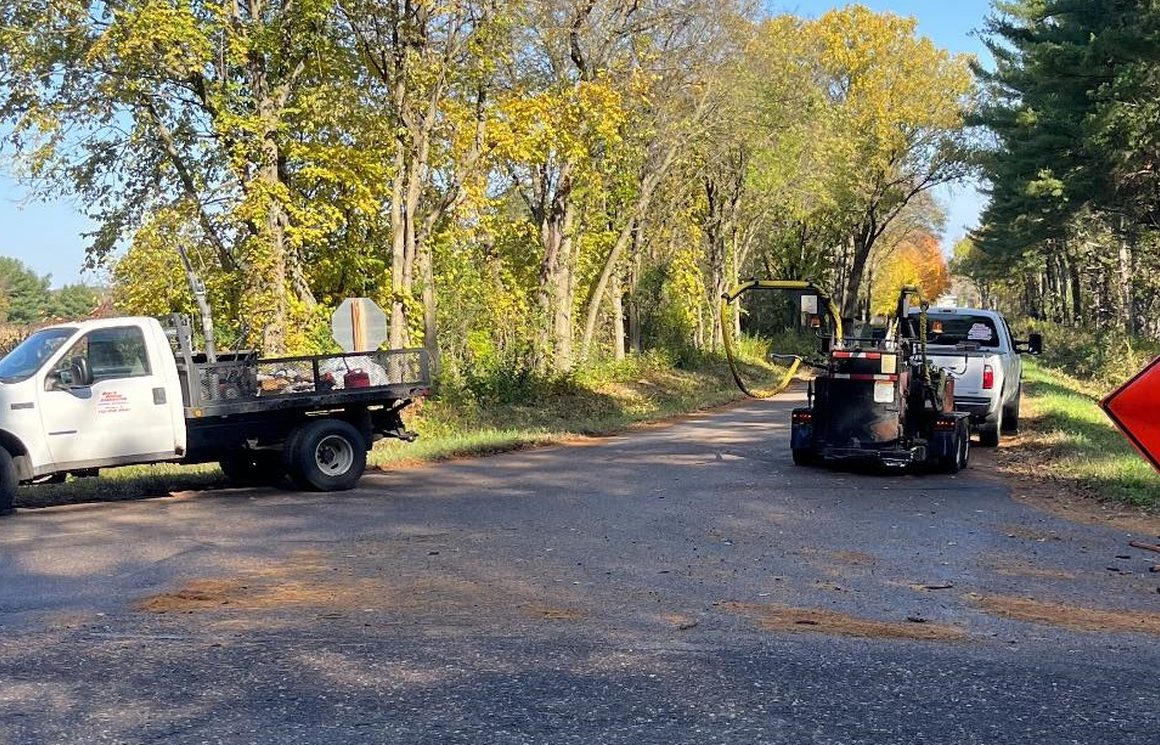 The crack crew's trucks and melter working a tree-lined road