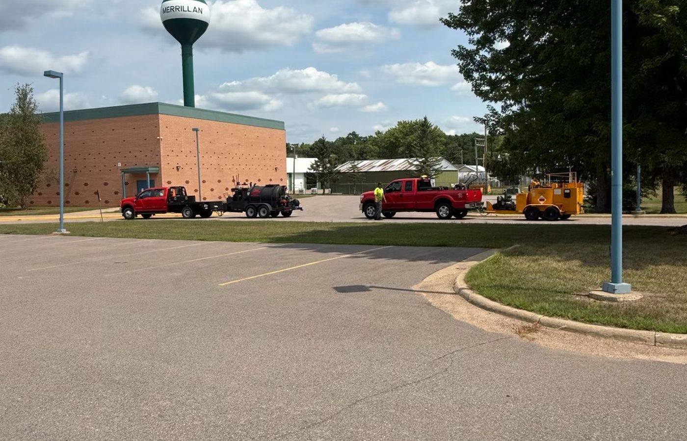 The company trucks and equipment staged on a lot, water tower beyond