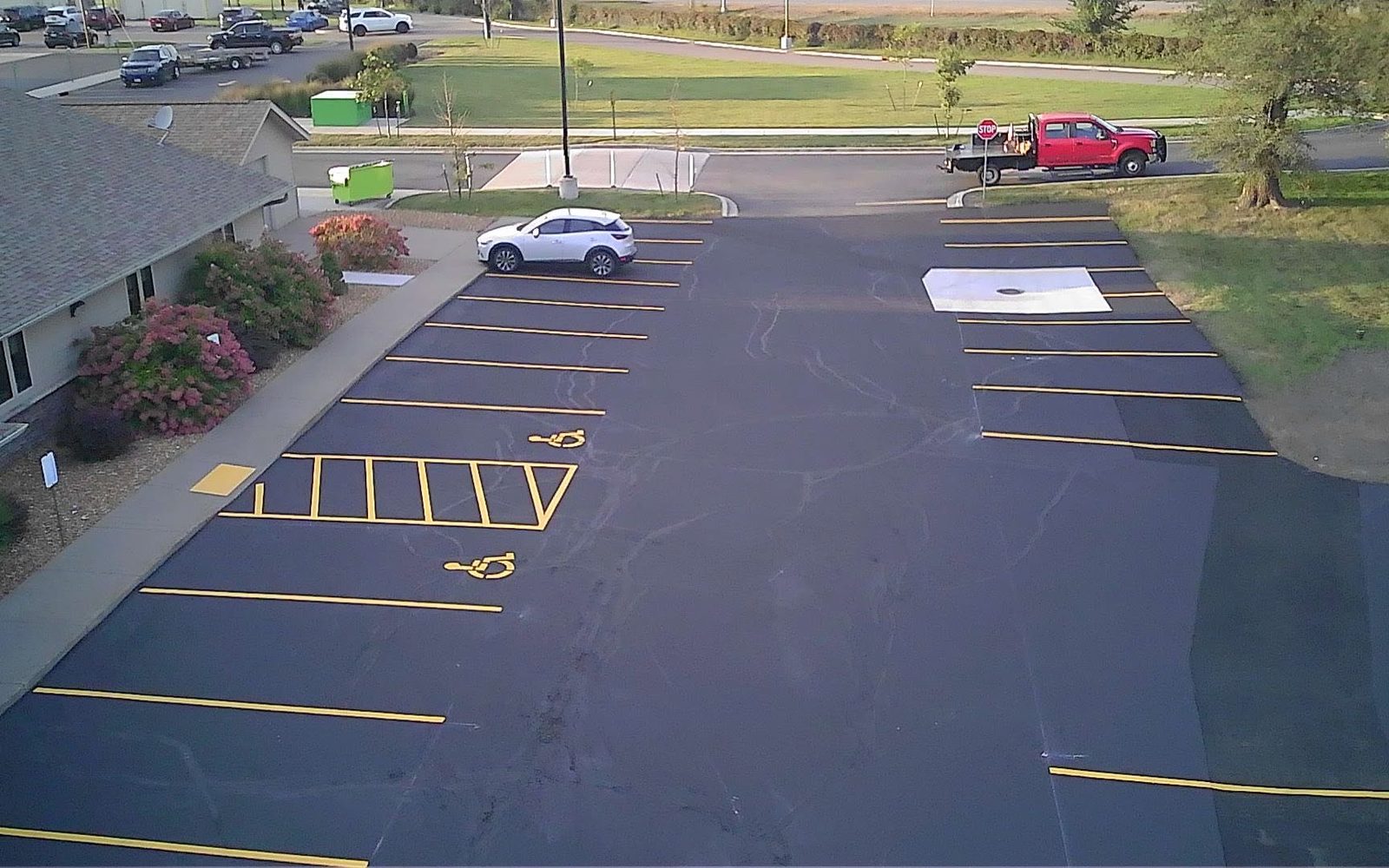 Overhead view of a freshly sealed lot with new yellow stripes, ADA stalls and a rebuilt catch basin