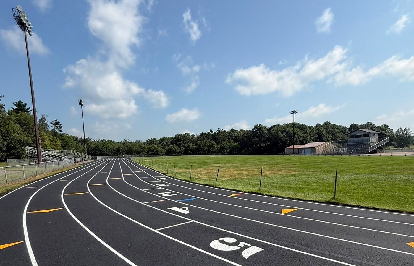 A resurfaced running track with fresh white lane lines, painted lane numbers and yellow exchange marks